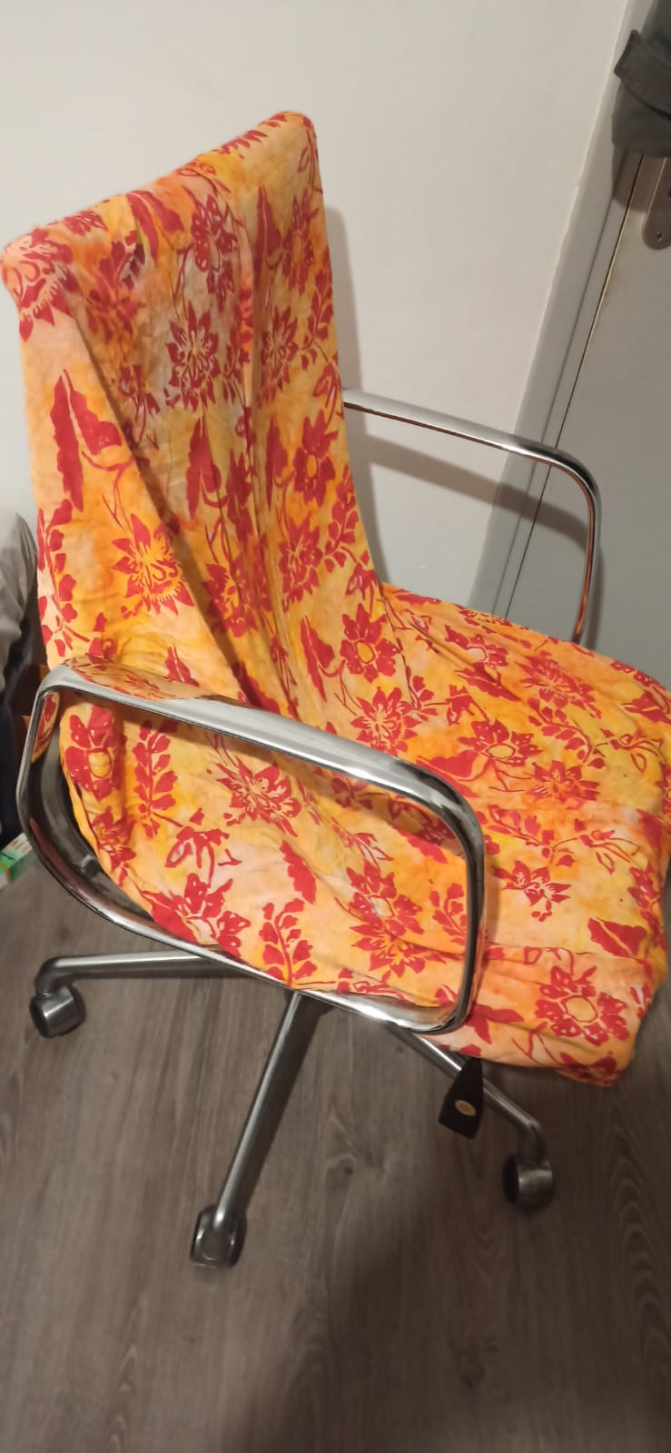 An office chair collected for free, covered with an orange and red patterned throw